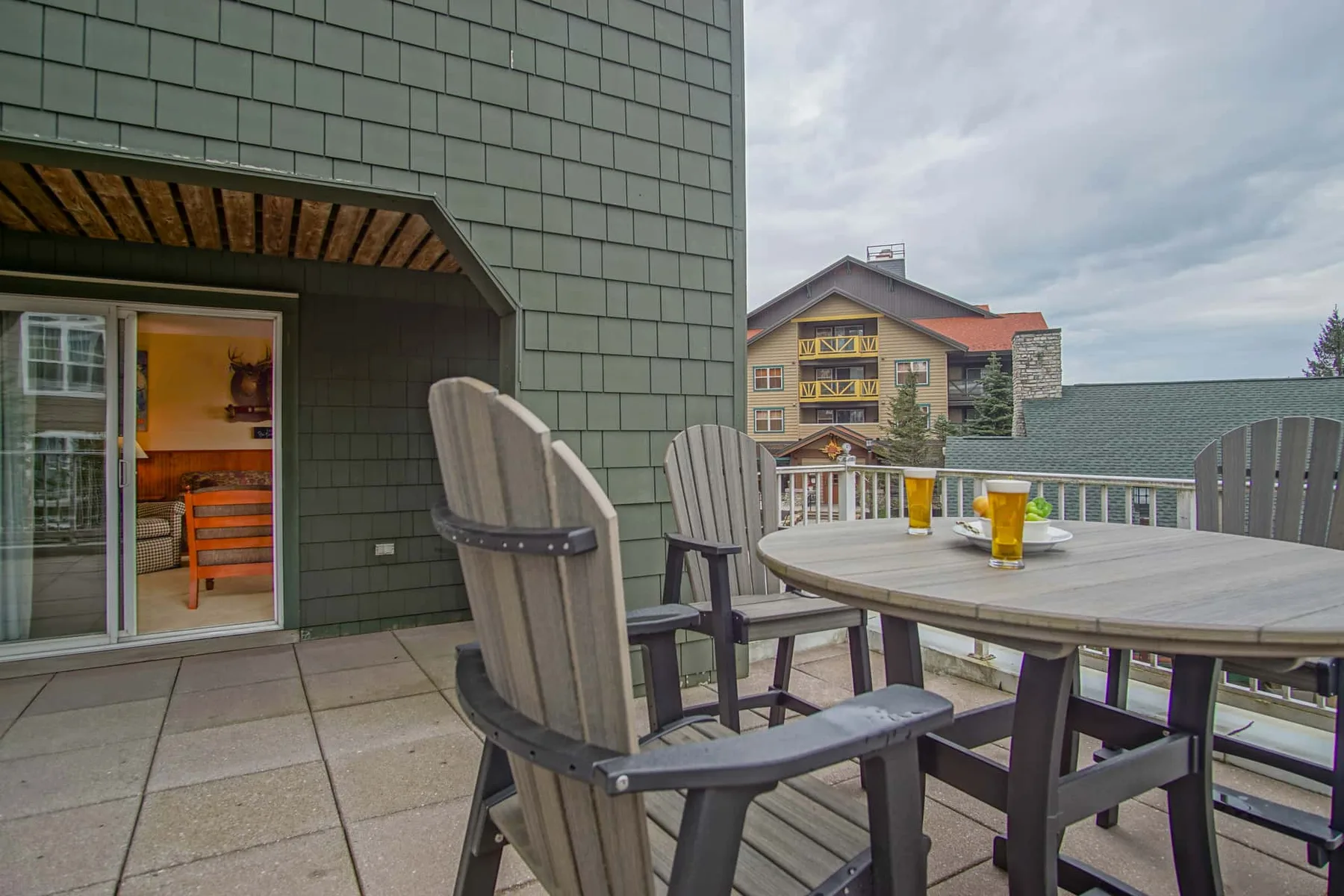 An outdoor patio has a dining table and seating beside a sliding glass door.