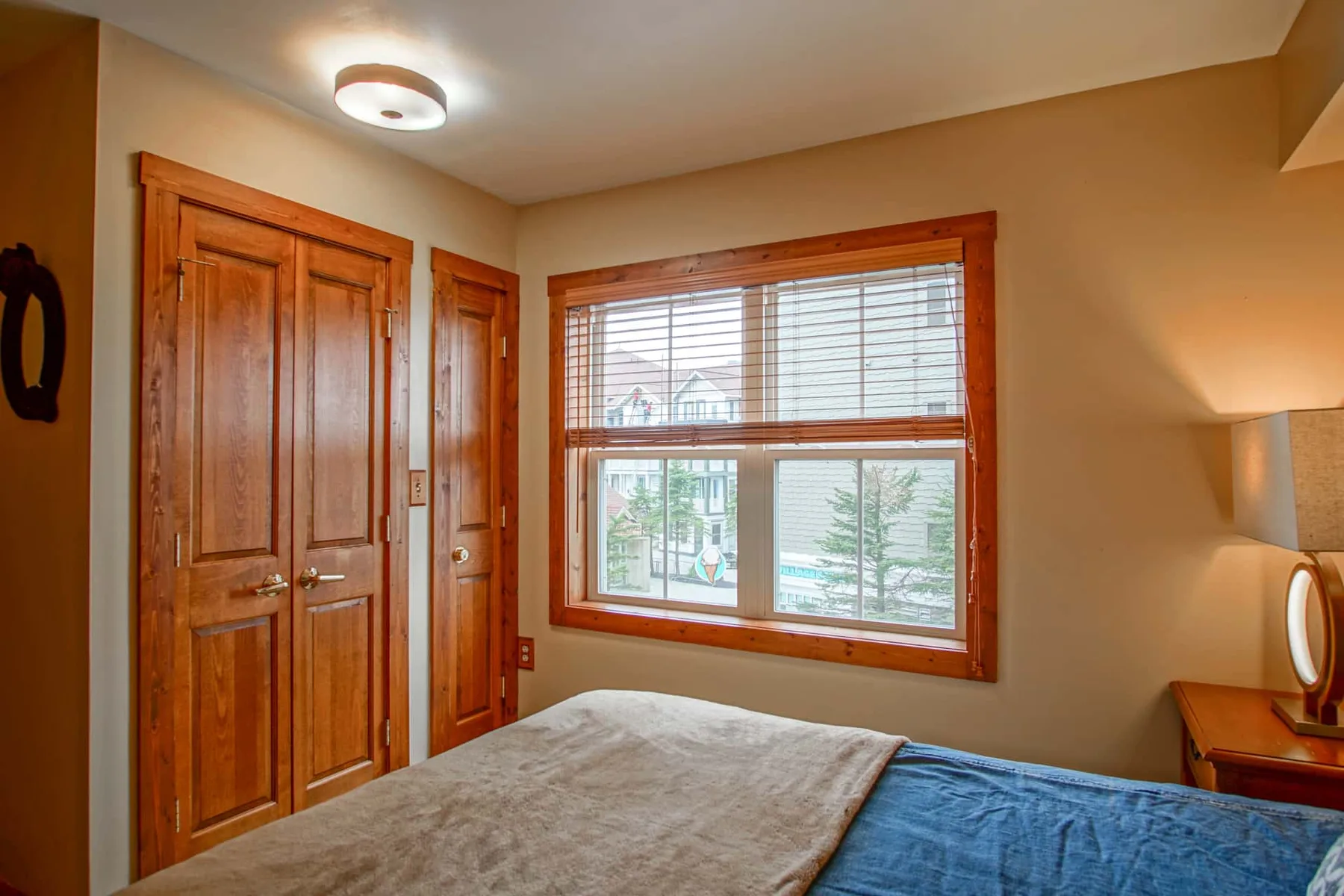 A bedroom with a bed beside a window with blinds.