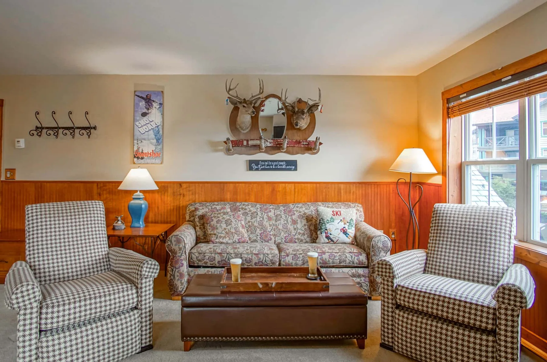 A living room with patterned seating, a coffee table, and a large window.