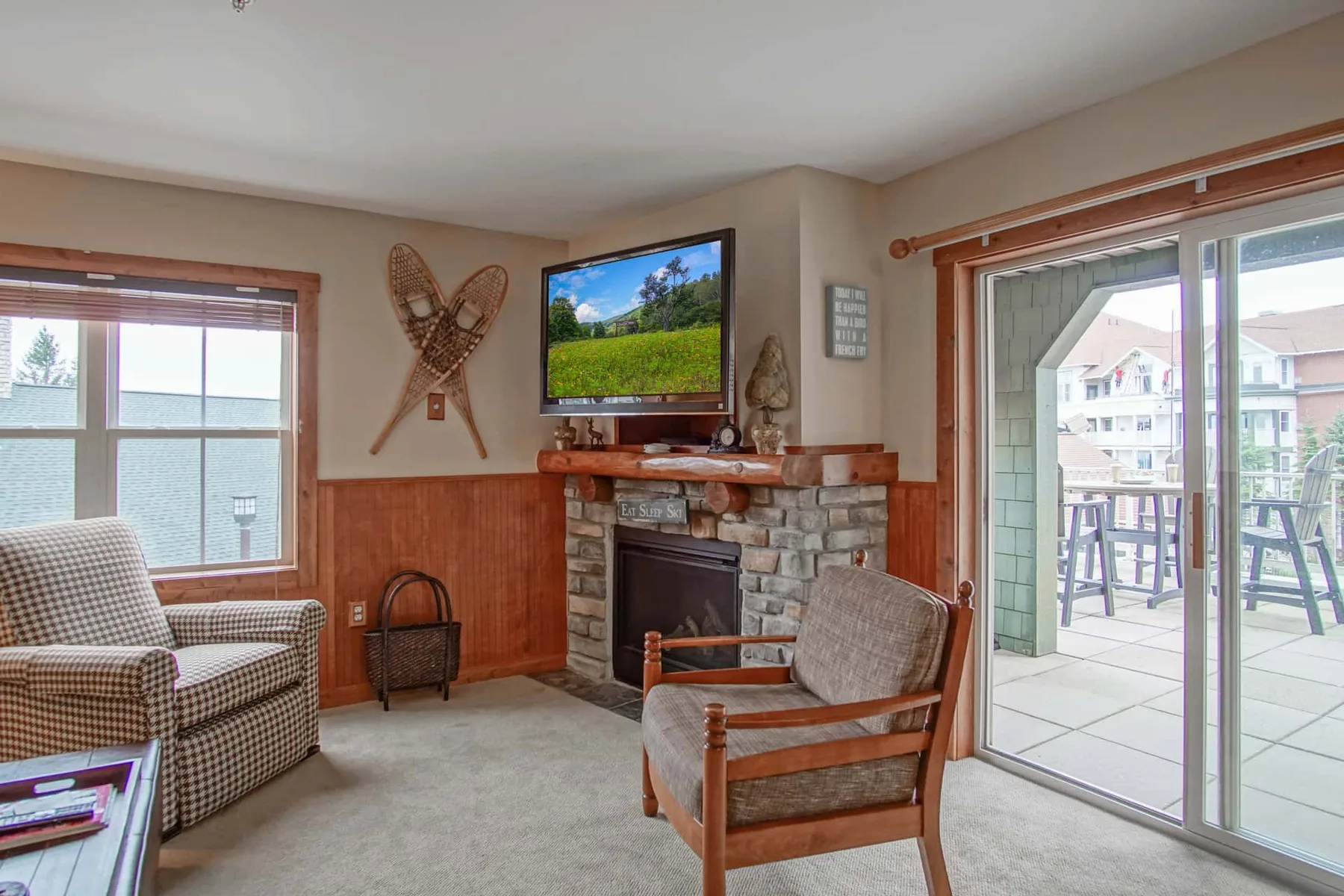 A living room with seating, a stone fireplace, and sliding glass doors opening to a patio.