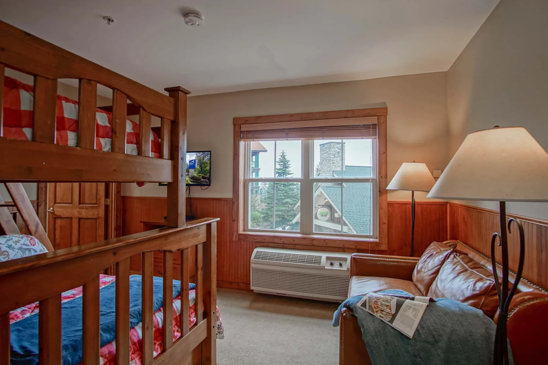 A bedroom with bunk beds, a window, and a seating area.