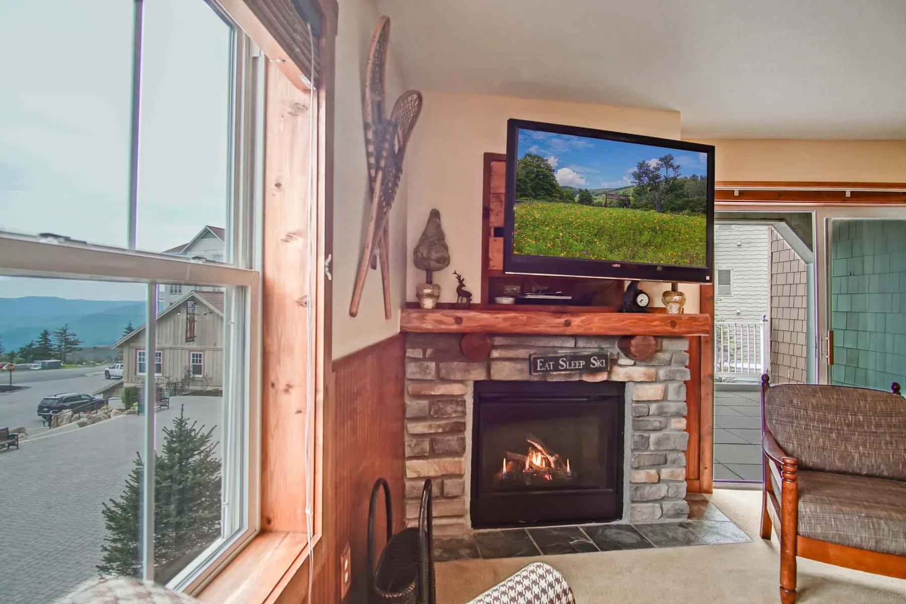 A living room with a stone fireplace and a large window overlooking the outdoors.