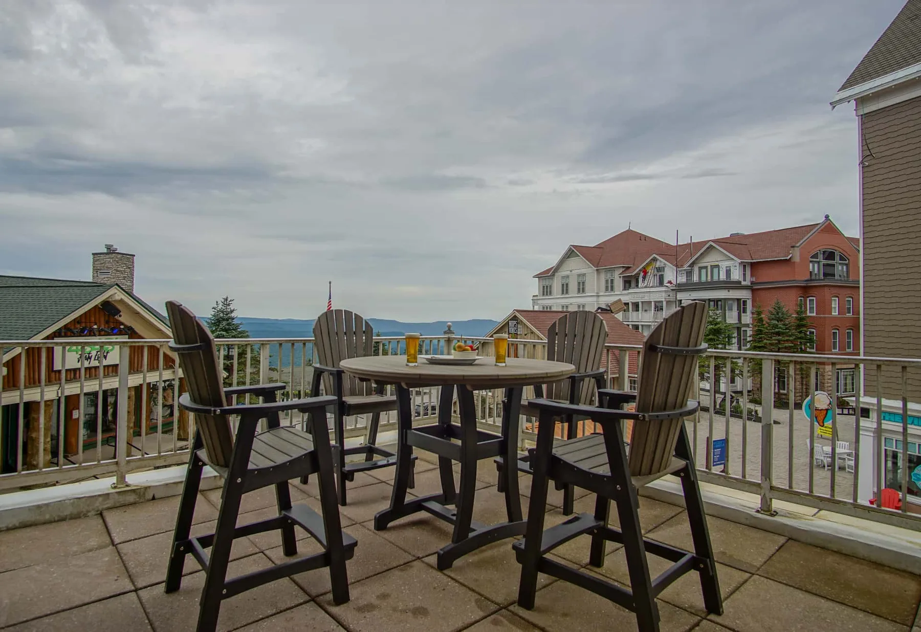 A rooftop terrace with outdoor seating overlooks nearby buildings and distant water.