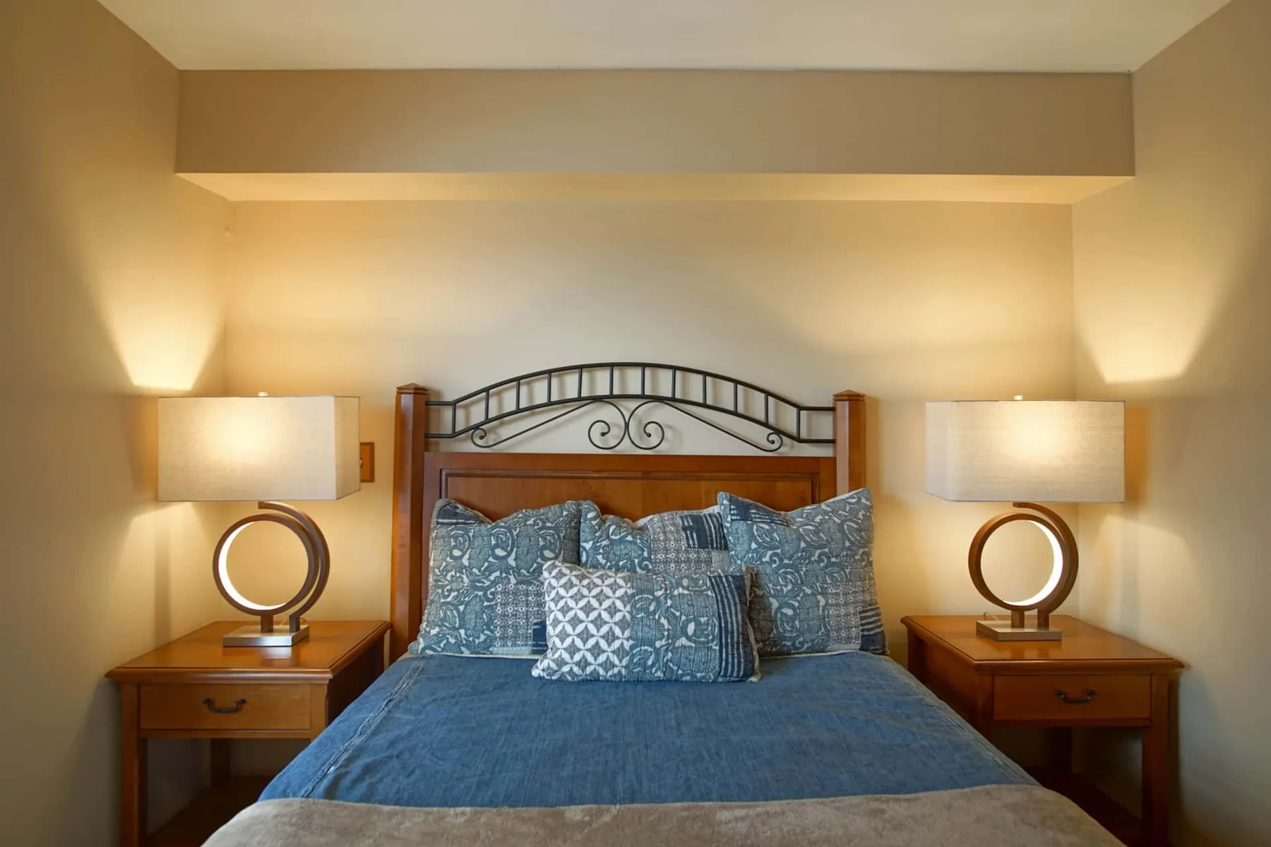 Bedroom with a bed dressed in blue bedding and matching bedside lamps.