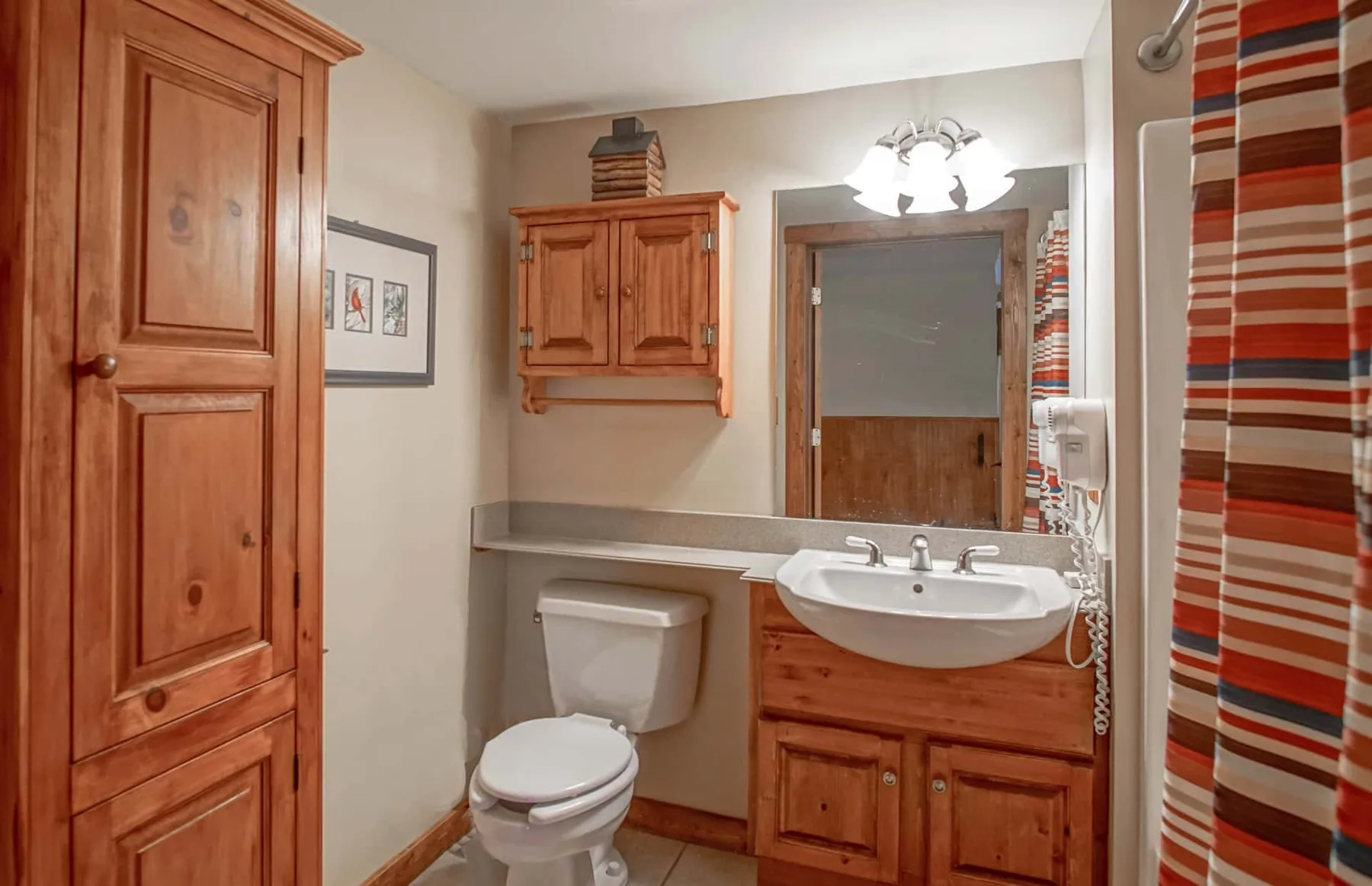 A bathroom with a toilet, wooden vanity, and sink beneath a mirror.