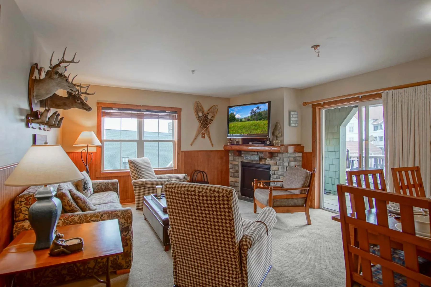 A living room with seating arranged around a stone fireplace and large windows.