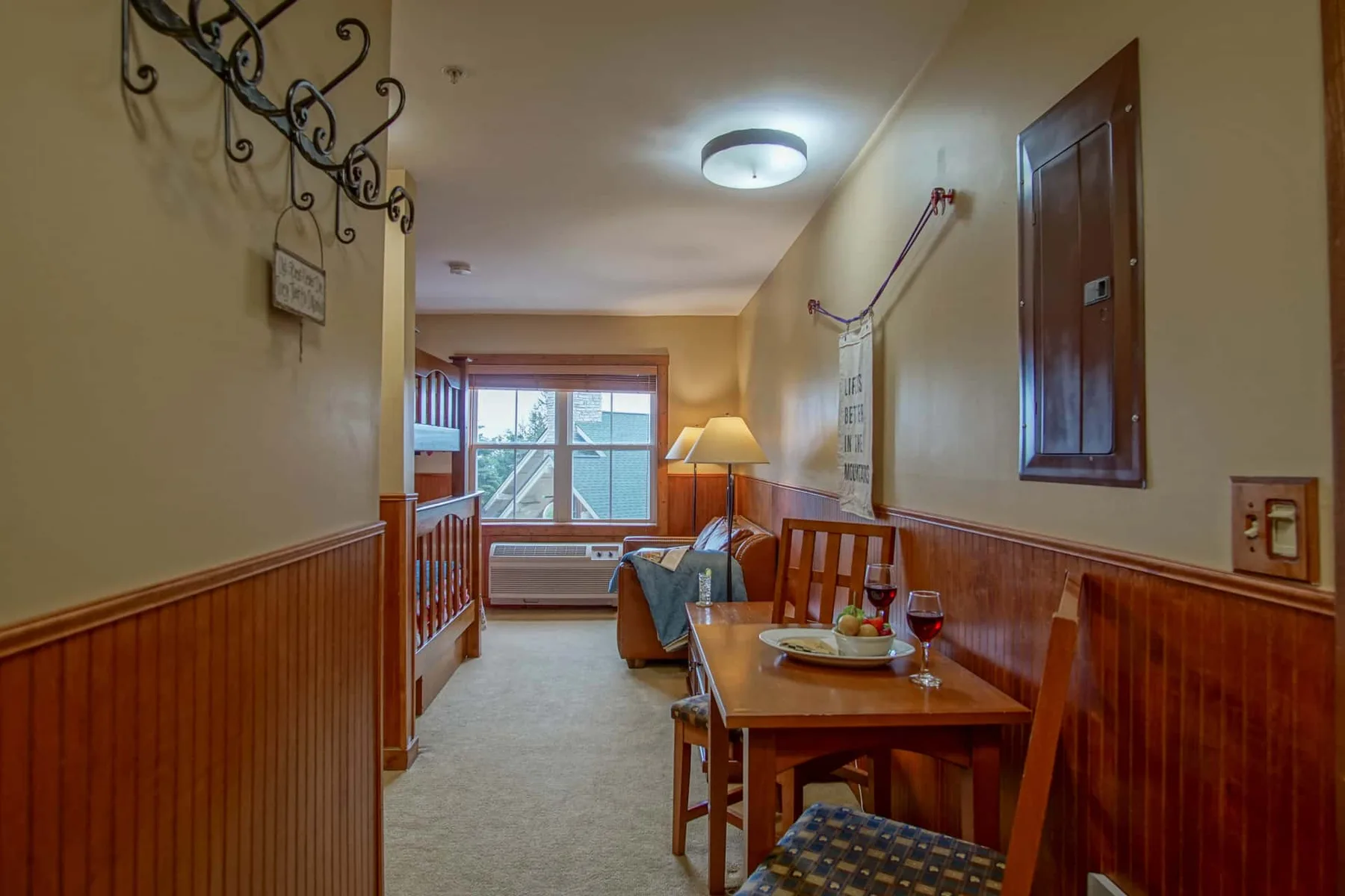 A narrow room with a dining table and seating beside a window.