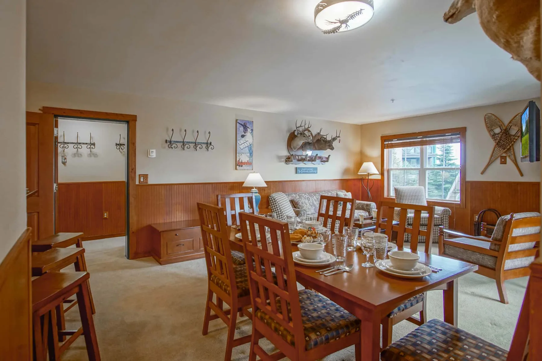 A dining room with a wooden table and chairs beside a large window.