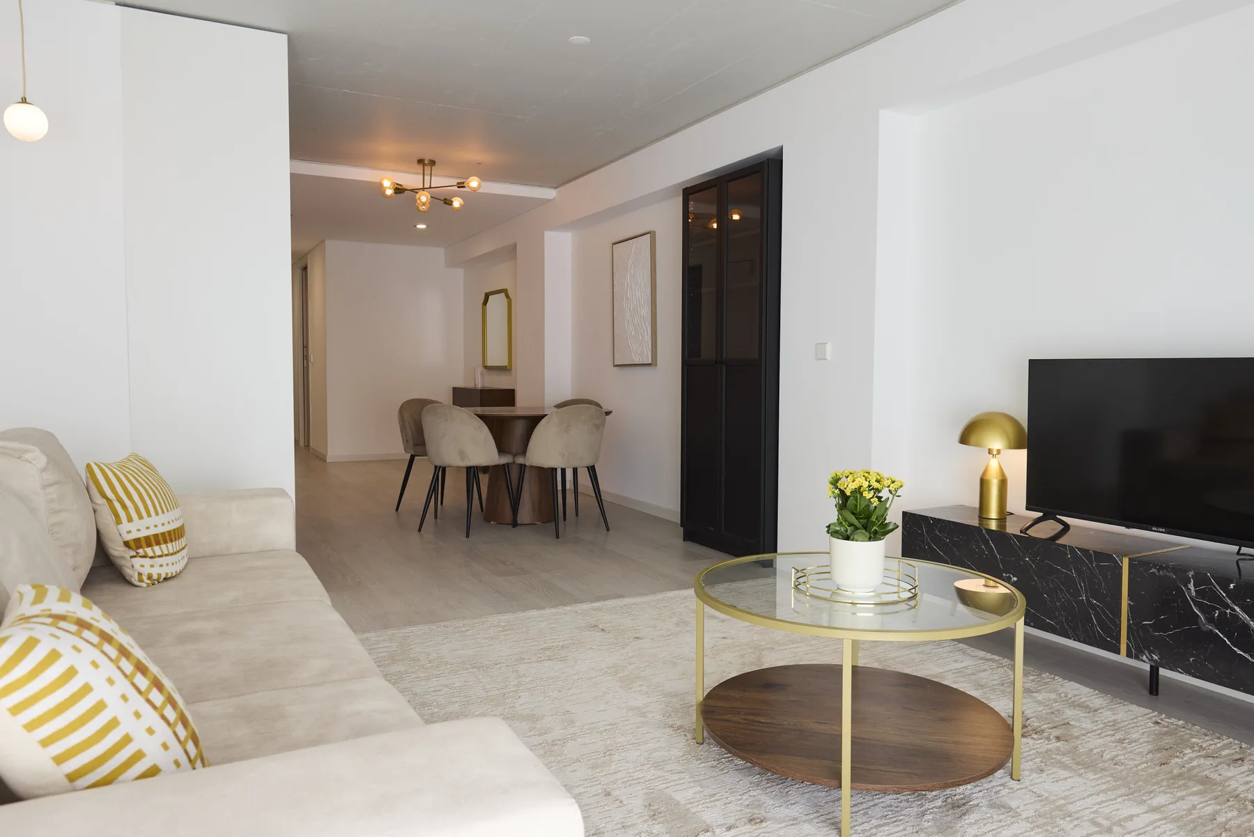 A bright living room with seating, a dining table, and a television.