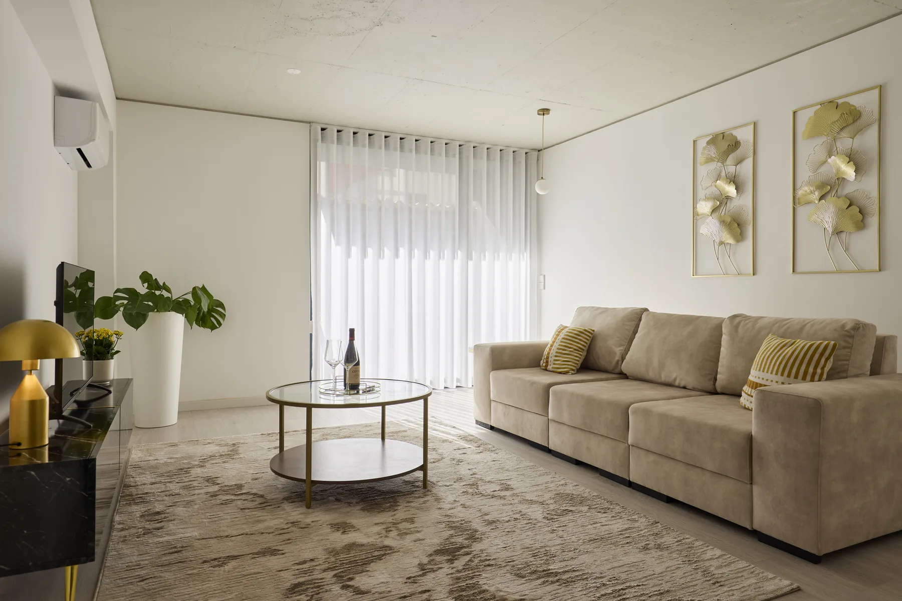 A living room with a sectional sofa, coffee table, and sheer curtains.
