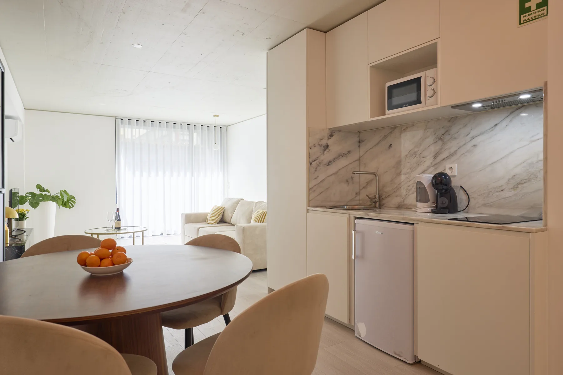 A bright open-plan kitchen and dining area with a living space by the window.
