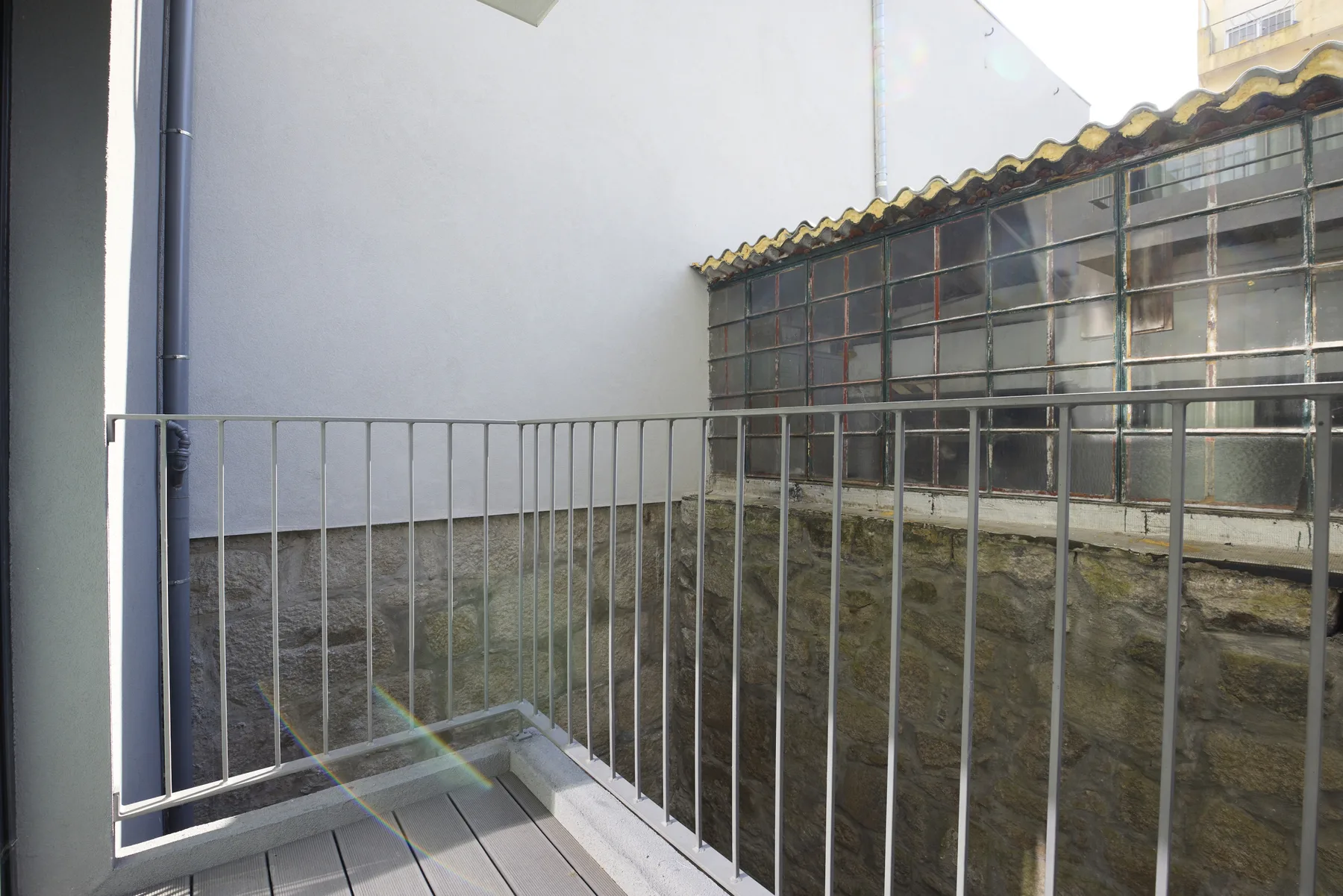 A small outdoor terrace overlooks a stone wall and a glass-block structure.