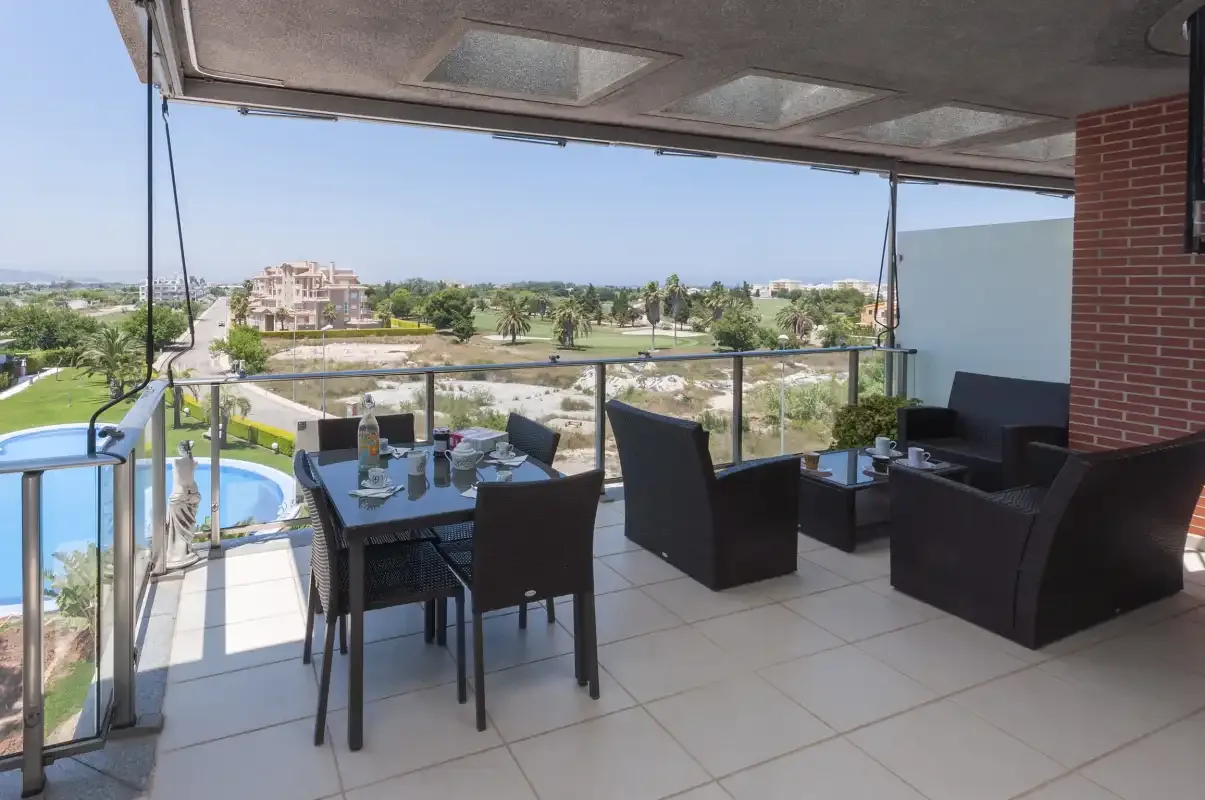 A covered terrace with outdoor seating overlooks a swimming pool and landscaped grounds.