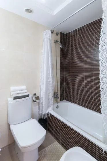 A bathroom with a bathtub, shower curtain, and toilet.