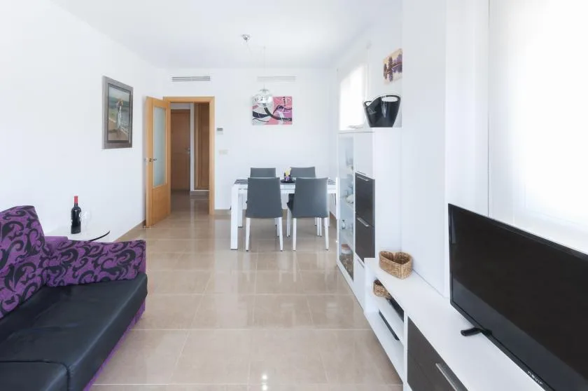 A bright living and dining area with a television and dining table.