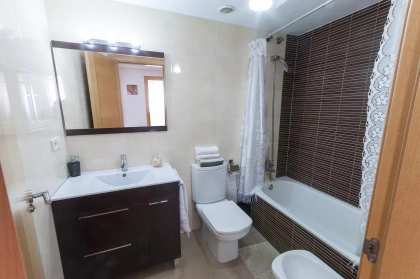 A bathroom with a sink, toilet, and bathtub behind a shower curtain.