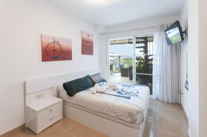 A bright bedroom with a bed and sliding glass doors opening onto a balcony.