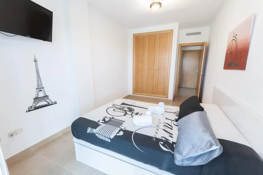A bedroom with a bed covered in black-and-white city-themed bedding.