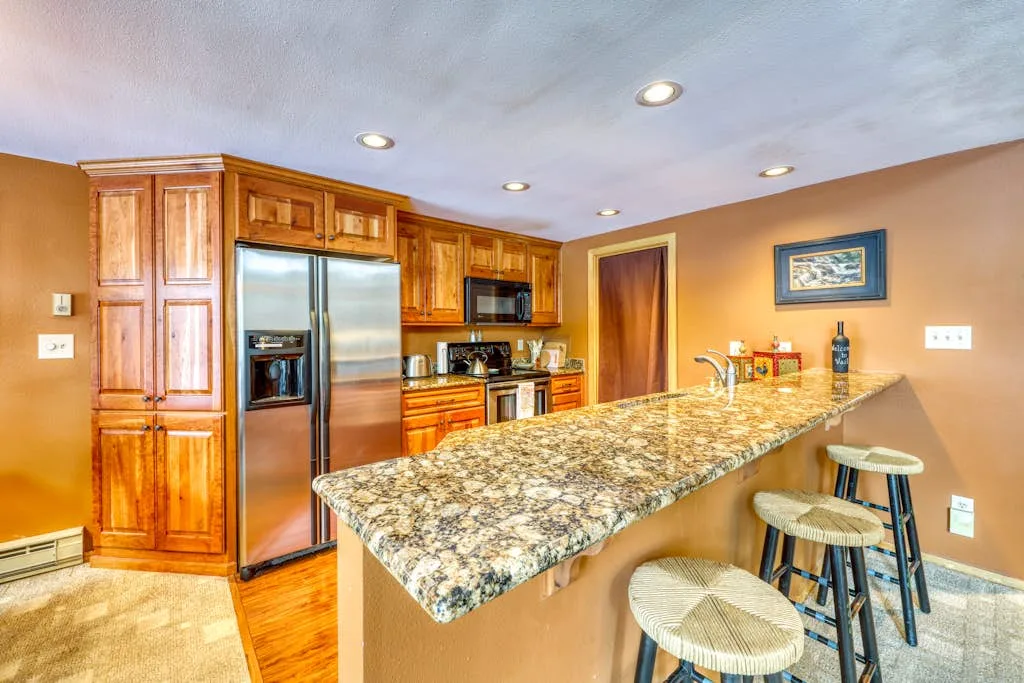 A kitchen with wooden cabinets and a long stone-patterned island.