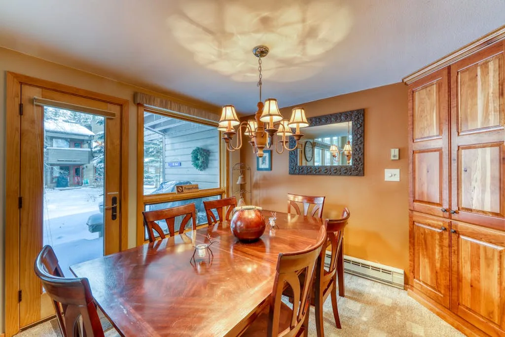 A dining room with a wooden table and chairs beneath a chandelier.