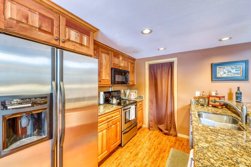 A kitchen with wooden cabinets, stainless steel appliances, and a central doorway.