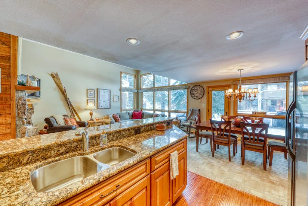 A kitchen and dining area with a stone-topped island and a wooden dining table.