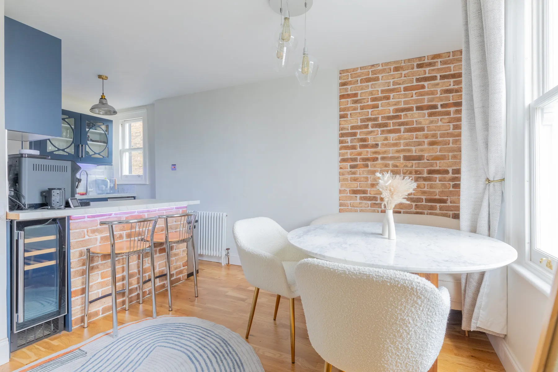 A bright dining area with a round table beside a kitchen counter.