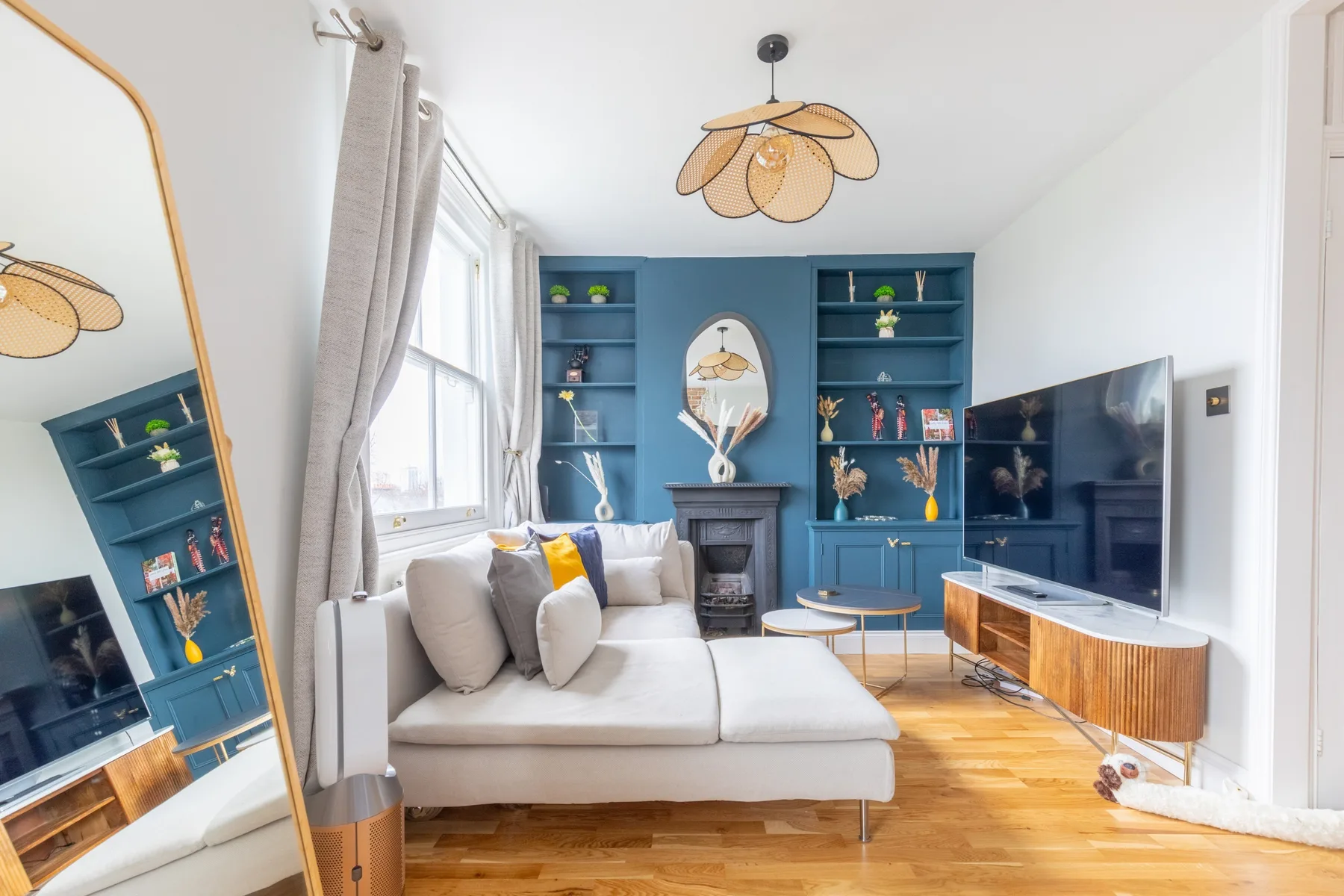 Una luminosa sala de estar con sofá seccional blanco y estantes empotrados azules.