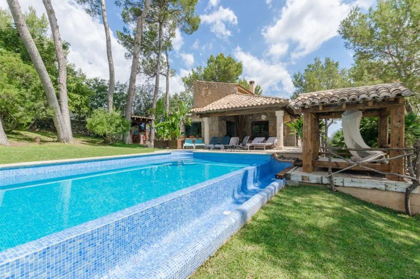 An outdoor swimming pool beside a covered patio and garden.