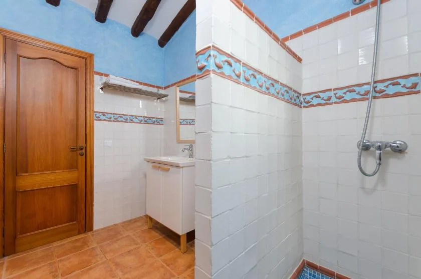 A tiled bathroom with a shower, sink, and wooden door.