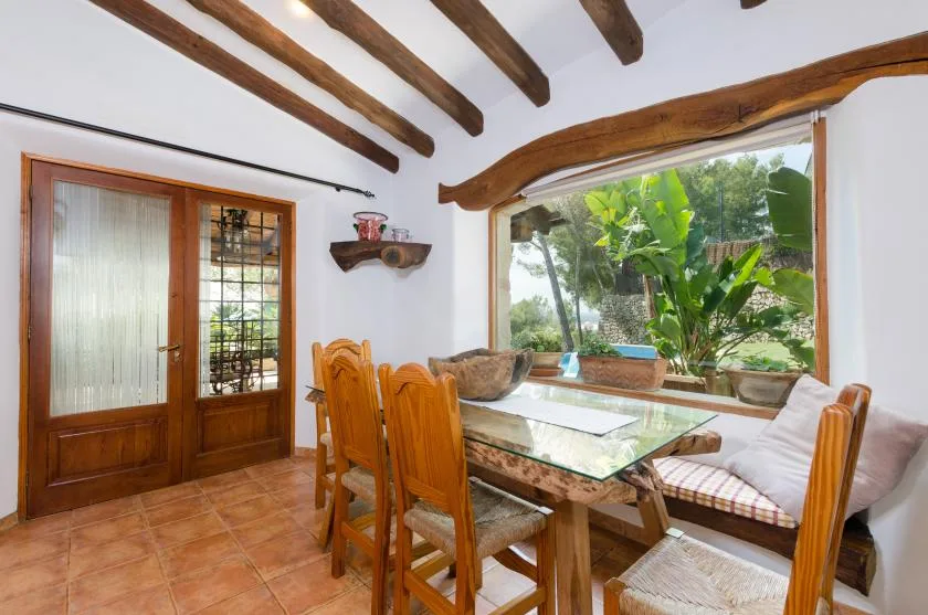 A dining area with a wooden table and chairs beside a large window.