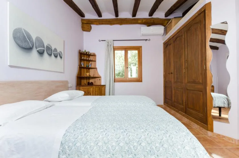 A bedroom with a bed, a wooden wardrobe, and a window.