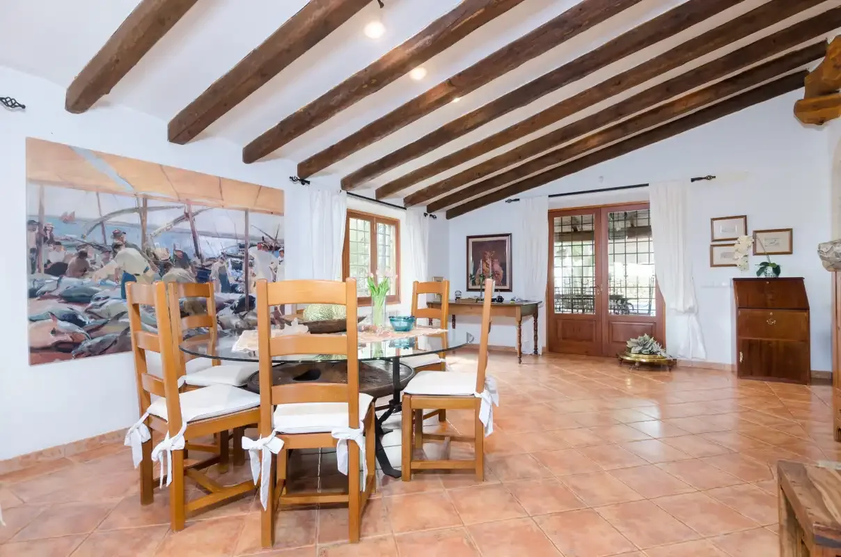 A dining area with wooden seating, a table, and exposed ceiling beams.