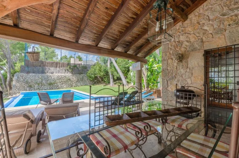 A covered outdoor dining area overlooks a swimming pool and garden.