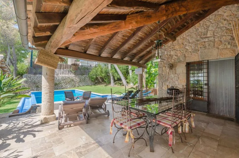 A covered patio with outdoor seating and a swimming pool beside it.