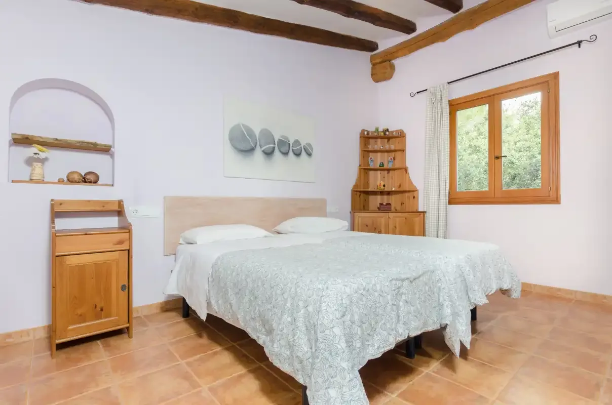 A bedroom with a double bed, wooden furniture, and a window.