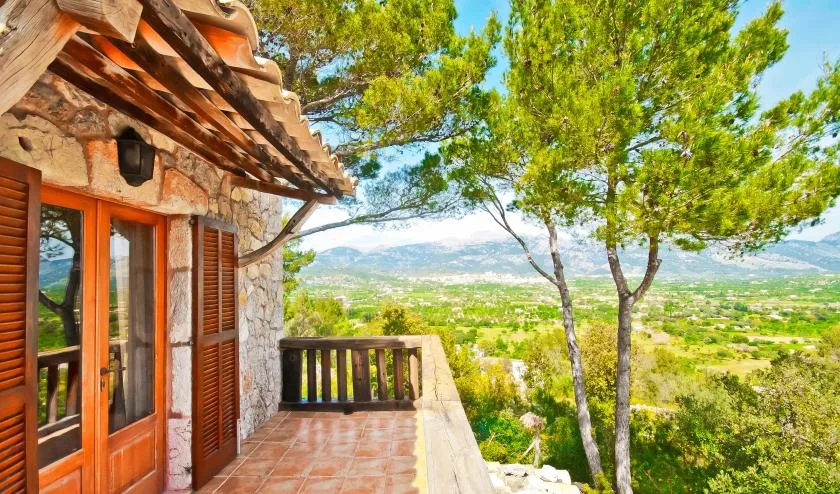 A tiled terrace beside a stone house overlooks a green valley.