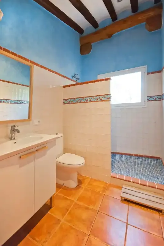 A bathroom with a sink, toilet, and tiled shower area.