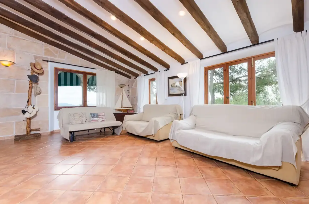 A living room with covered seating and exposed wooden ceiling beams.