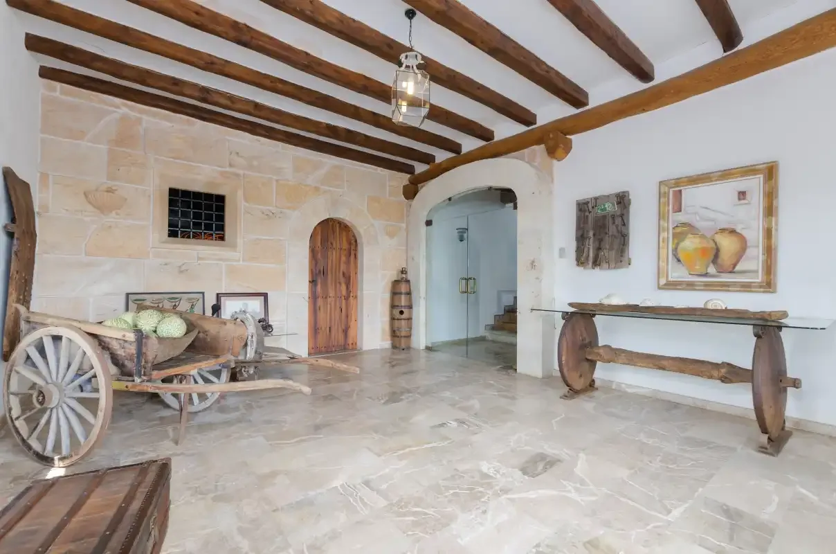 A rustic interior hall with exposed wooden beams and stone walls.