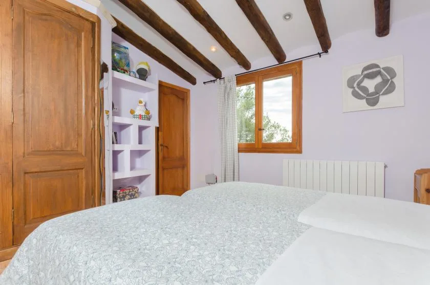 A bedroom with a bed, wooden doors, and a window.