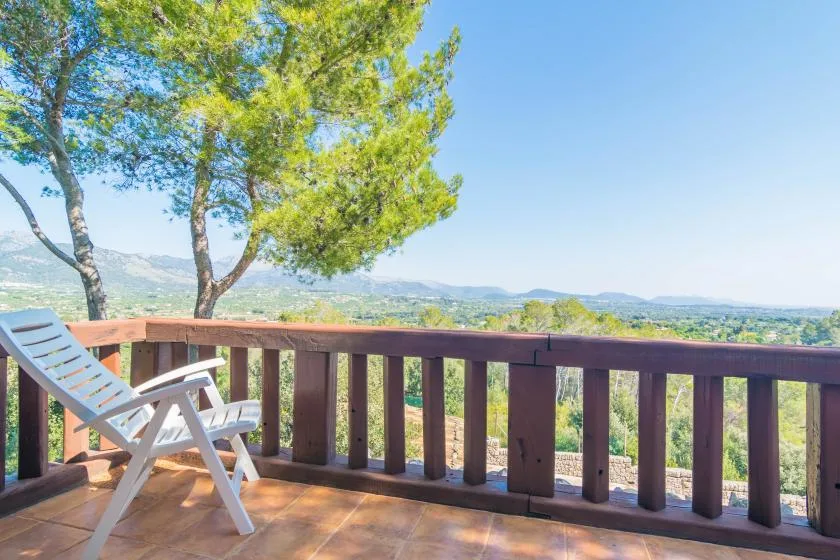 A wooden deck with seating overlooks a tree-covered landscape.