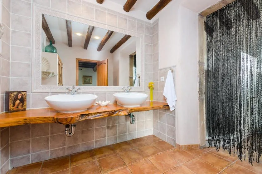 A tiled bathroom vanity with two vessel sinks sits beside a shower.