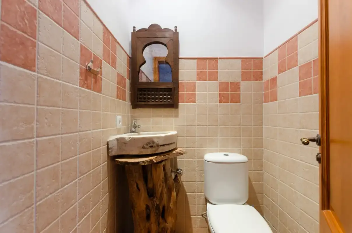 A tiled bathroom with a rustic wooden vanity and a toilet.