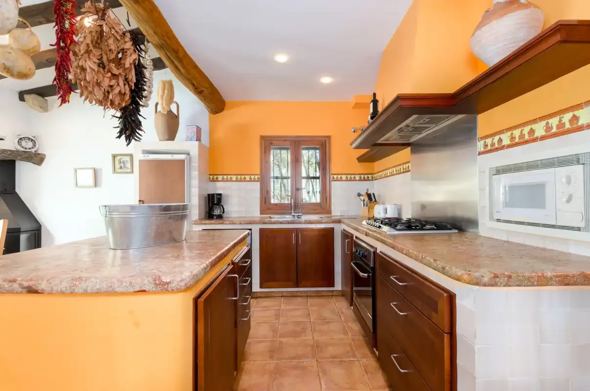 A bright kitchen with orange walls, dark cabinets, and a central island.
