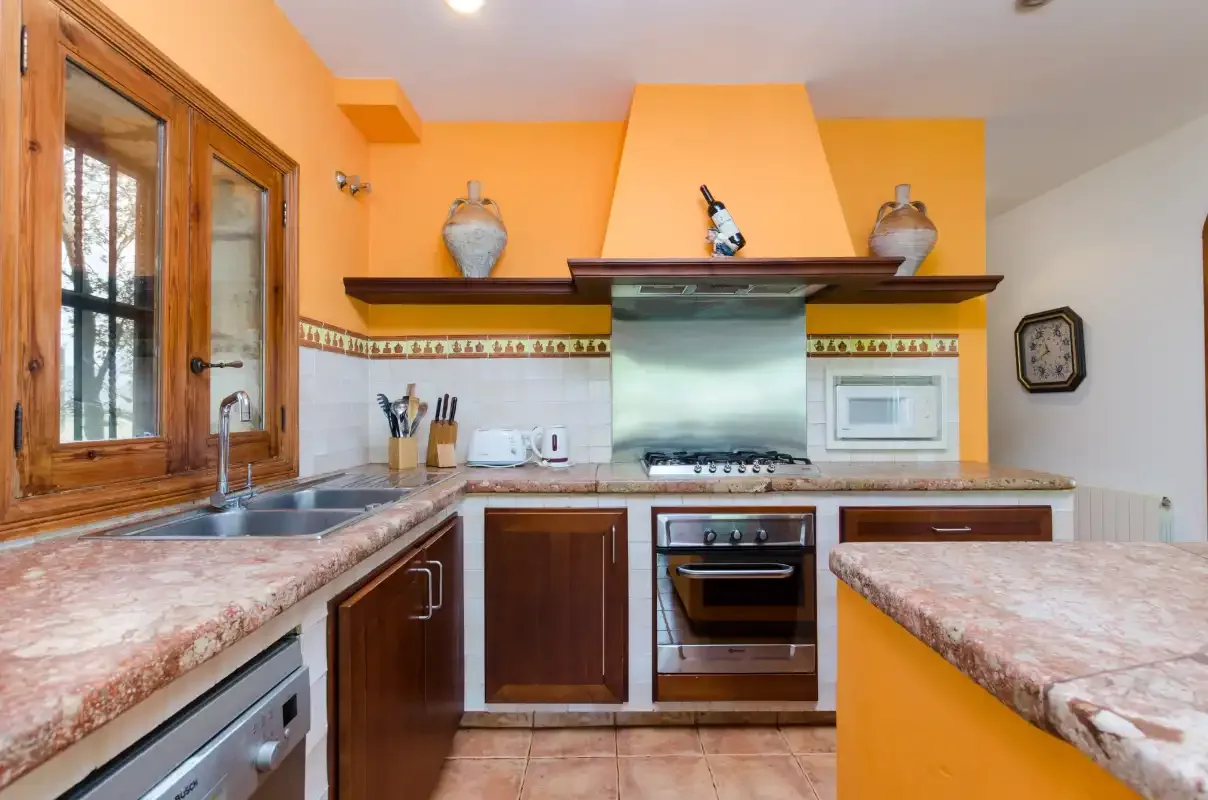 A bright kitchen with wood cabinets, a central cooktop, and stone countertops.