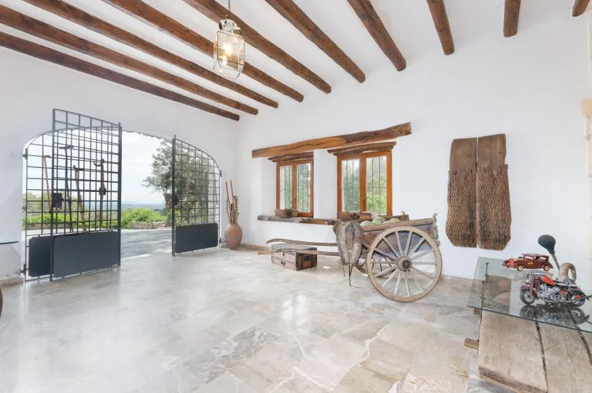 A bright interior with exposed wooden ceiling beams and an open metal gate.