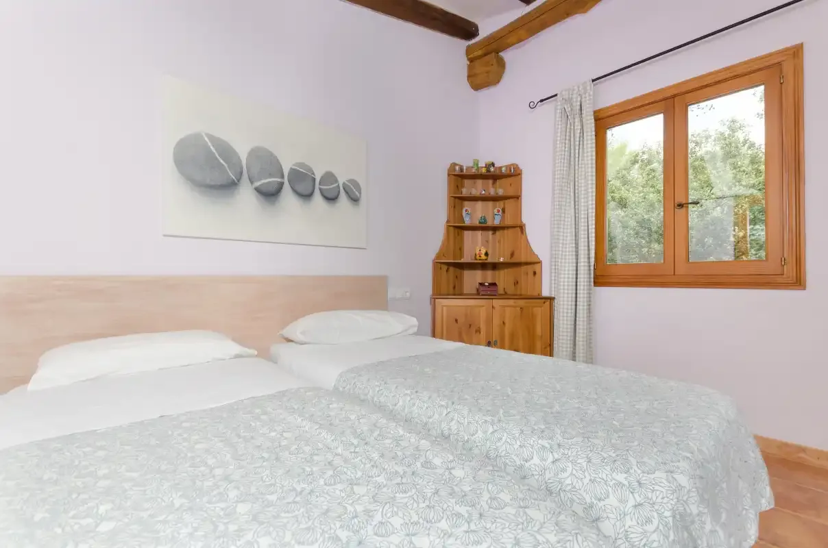 A bedroom with two beds, a wooden cabinet, and a window.
