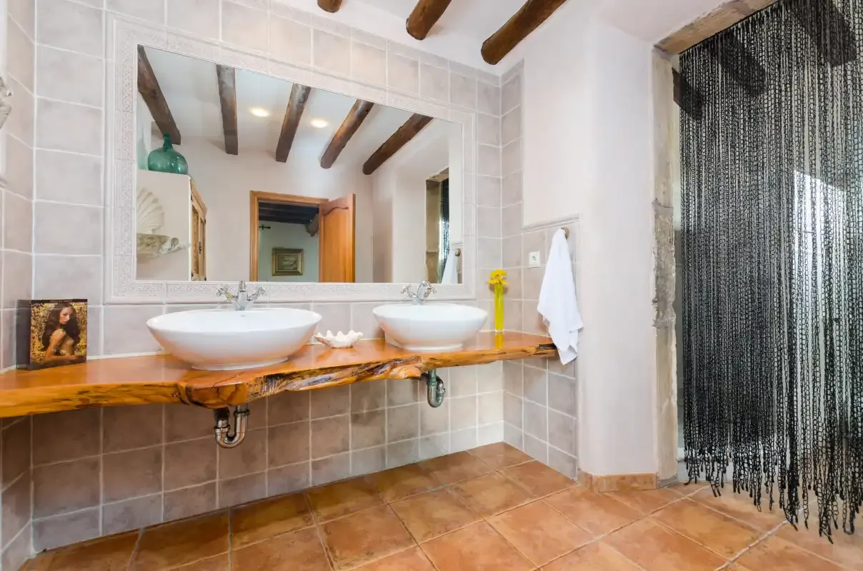 A tiled bathroom with two sinks beneath a large mirror.