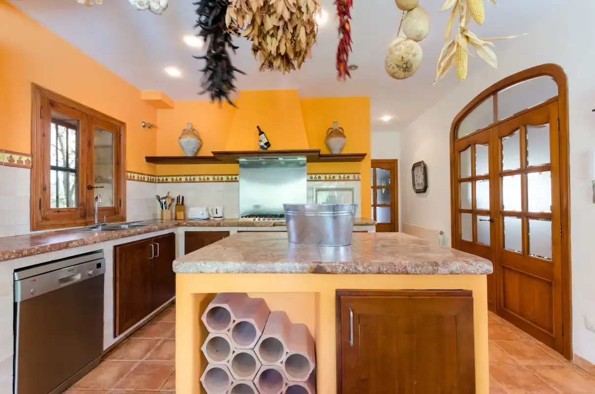 A warm-toned kitchen with a central island and wooden cabinetry.